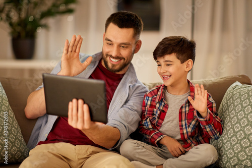 family, technology, communication and people concept - happy father and little son with tablet pc computer having video chat at home