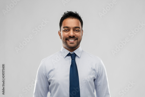 business, office worker and people concept - smiling indian businessman in shirt with tie over grey background