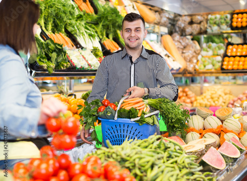 Glad seller helping customer to buy vegetables