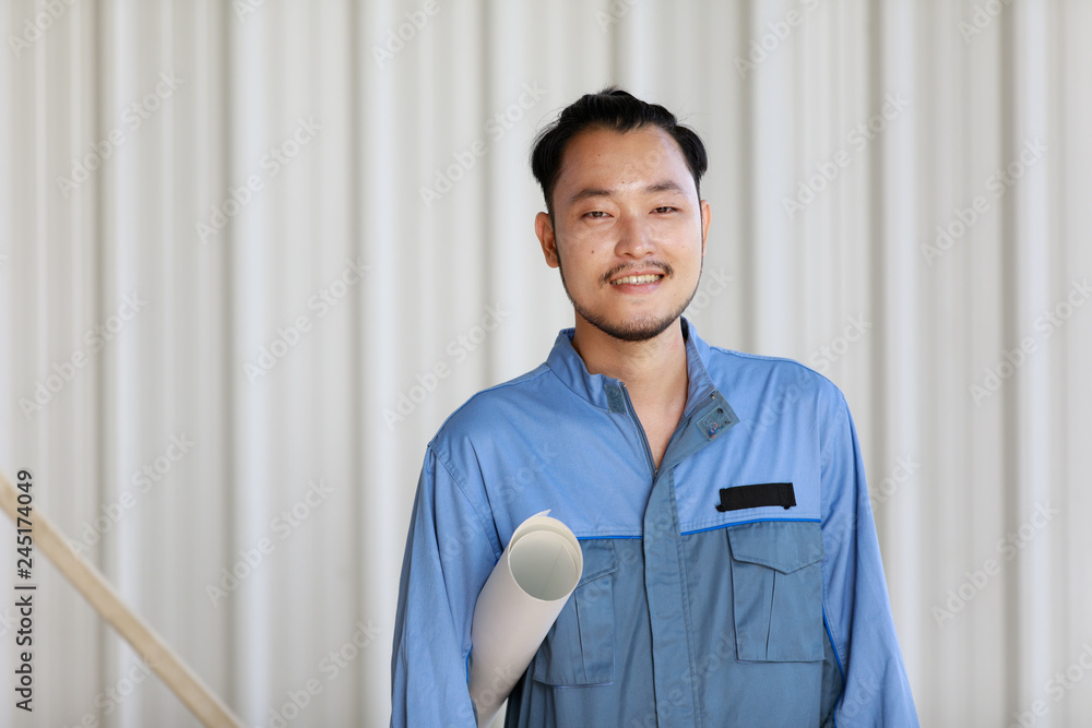 Obraz premium Portrait of male engineer with self-confidense and friendly manner, holding roll paper in hand