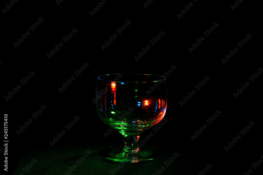 Empty glass in colorful lights on black background Empty glass in colorful lights on black background