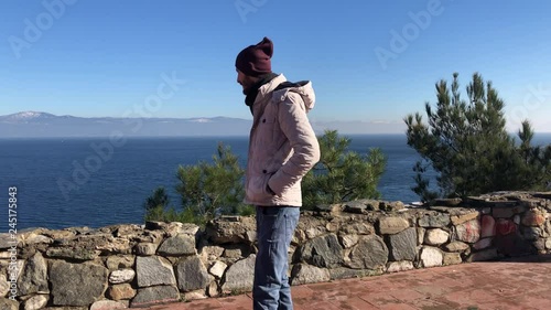 Young attractive man watching the beautiful coast and mountain view from the top of town.