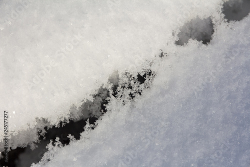 deep dark crack in clear sparkling snow cover © akintevs
