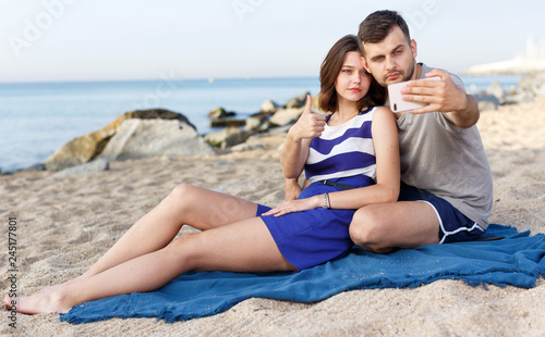 Positive loving couple resting and taking selfie