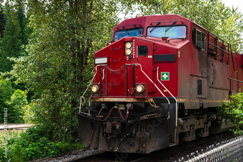 View of a Powerful Red Diesel Locomotive Pulling a Cargo Train on a Sunny Summer Day