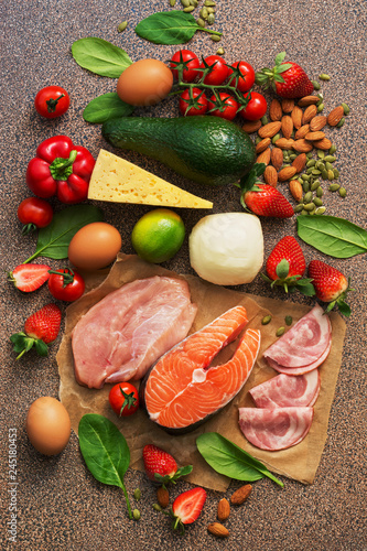 Keto diet concept.Healthy foods low in carbohydrates. Salmon, chicken, vegetables, strawberries, nuts, eggs and tomatoes, cutting board. Top view.