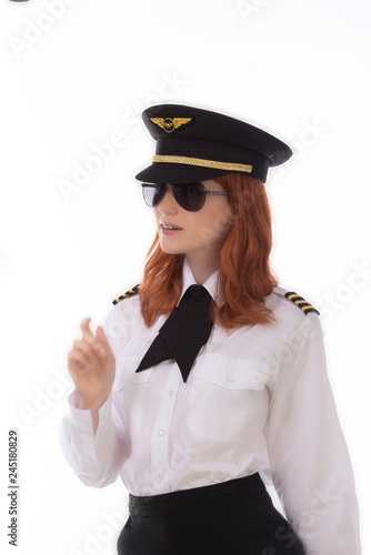 Young female pilot with red hair standing in airline uniform including a hat photo