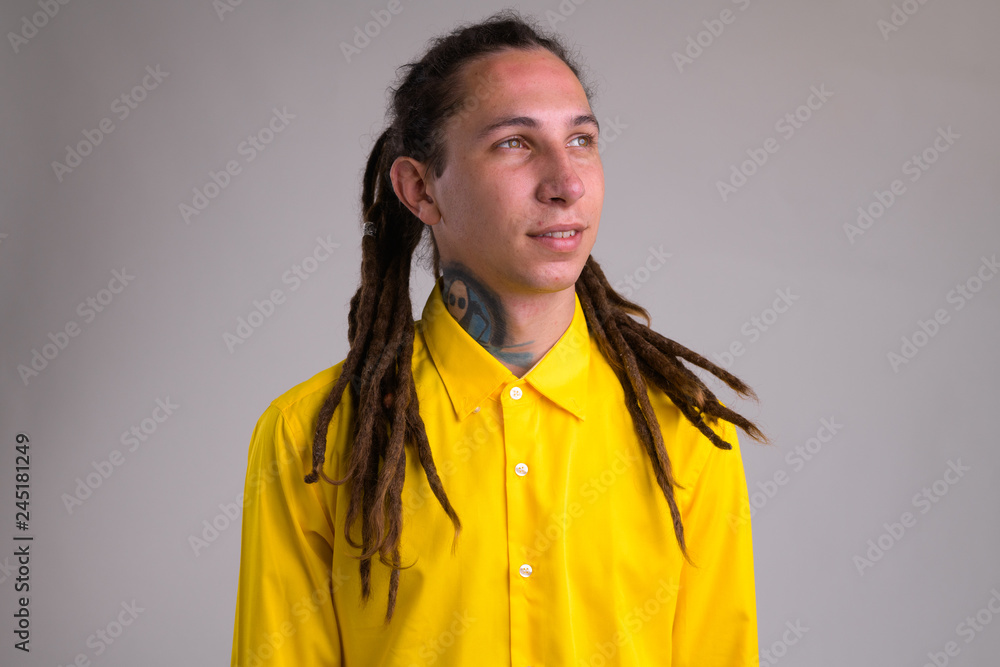 Fototapeta premium Face of young happy businessman with dreadlocks thinking