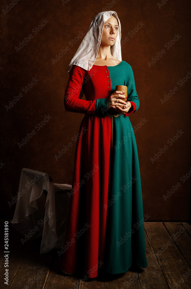Portrait of a beautiful girl in a medieval dress in red and green on a brown background. Portrait of a beautiful girl in a medieval dress in red and green on a brown background.