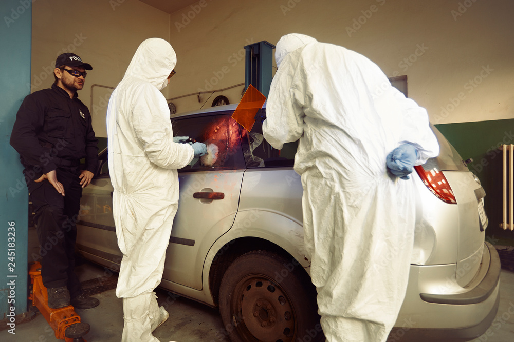 Crime investigation - developing of fingerprints on suspected car in police garage under UV light Crime investigation - developing of fingerprints on suspected car in police garage under UV light