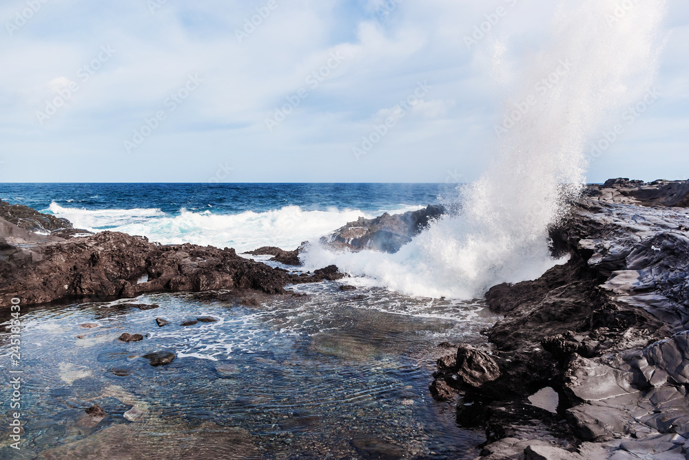 Waves breaking on the rocky coast of the Canary Islands. Tourism, travel, vacation, sea cruise.