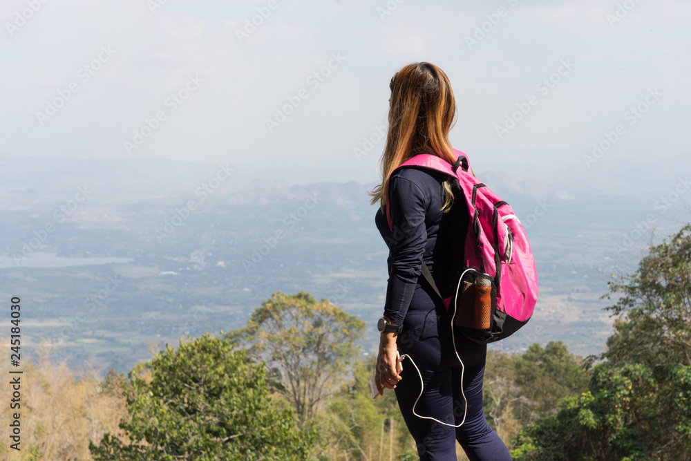 Asian woman with pink backpack standing looking at mountain view