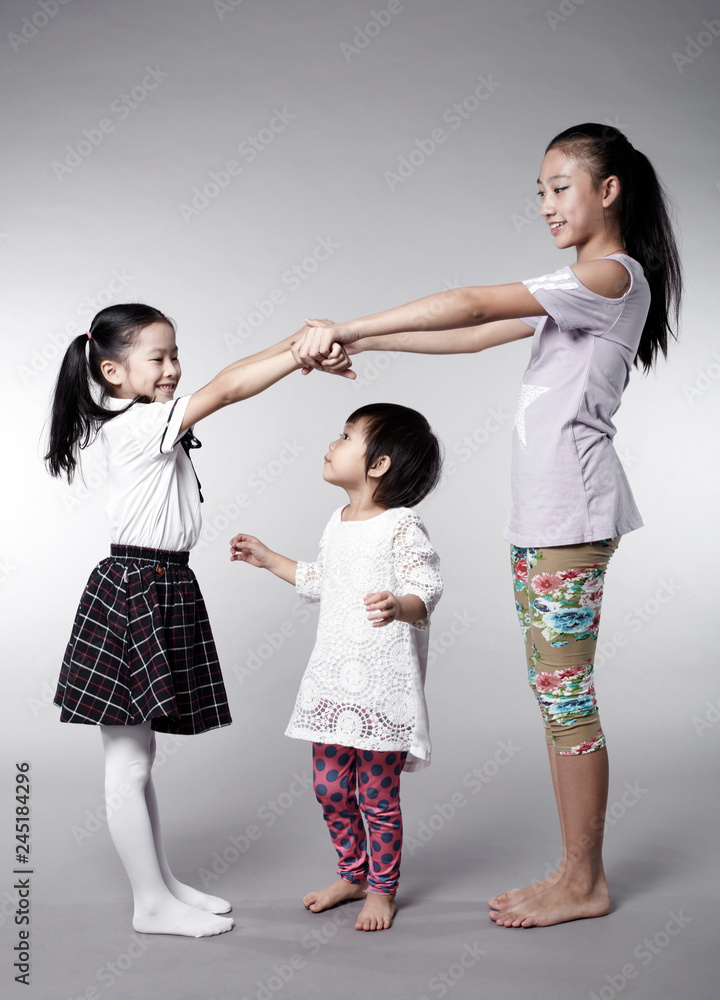 Three cute Asian Chinese little girls interacting happily, indoors with white background Three cute Asian Chinese little girls interacting happily, indoors with white background