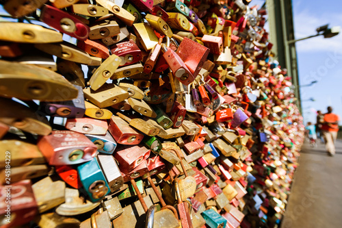 Love locks on a bridge, people in bokeh on background