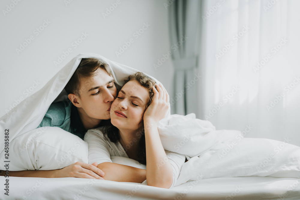lovely couple  in love kissing in bed - obrazy, fototapety, plakaty 