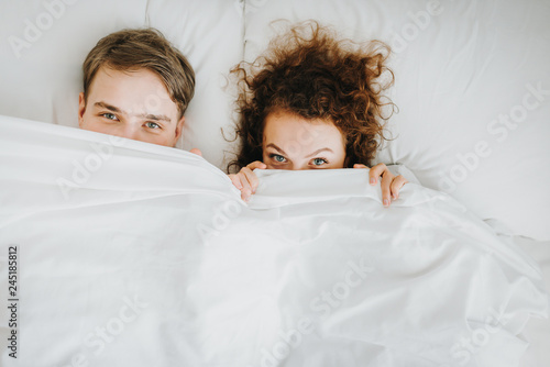 fuuny couple hiding under white blanket