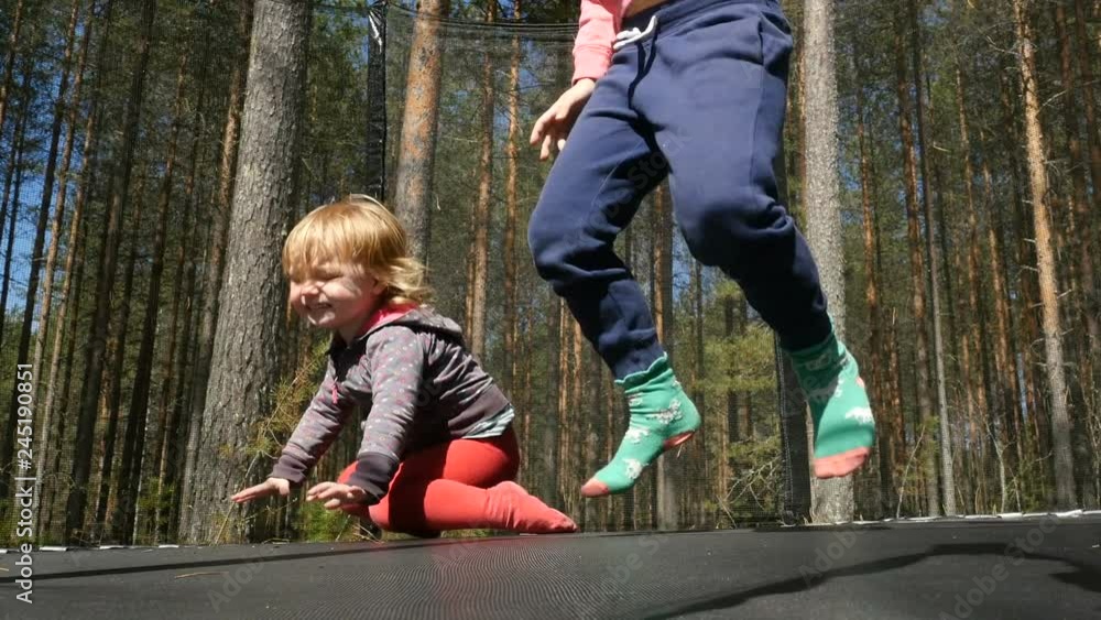 Kids, little girls, jump on trampoline in park at summer day Kids, little girls, jump on trampoline in park at summer day