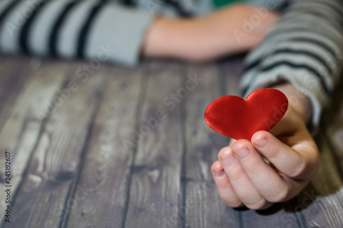 A child s hand holds a heart close-up.