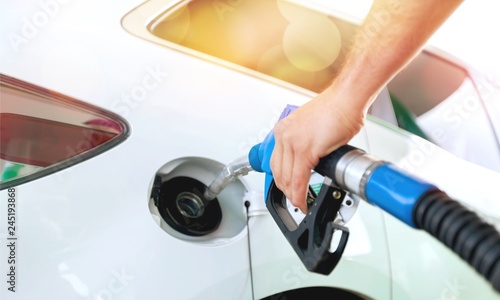 Pumping gas at gas pump. Closeup of man pumping gasoline fuel in