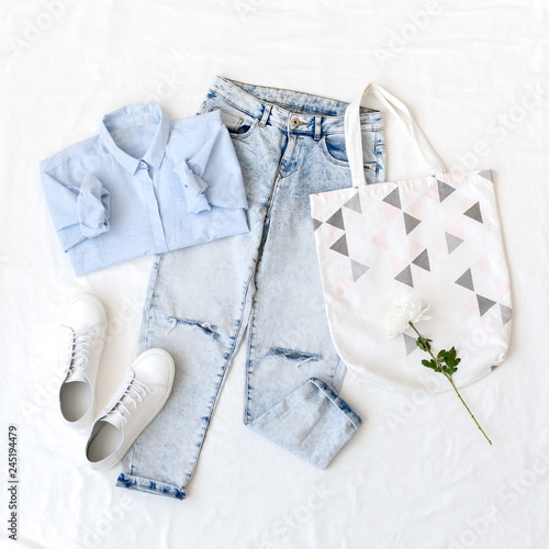 Blue Shirt Ripped Jeans White Sneakers Cotton Textile Bag Lying On The White Sheet Overhead View