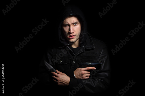Portrait of serious man with gun and knife in the hood black