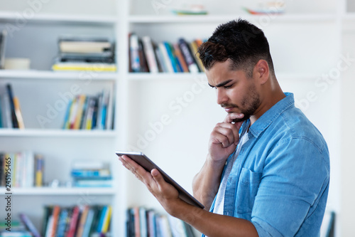 Thinking mexican hipster man with beard and tablet