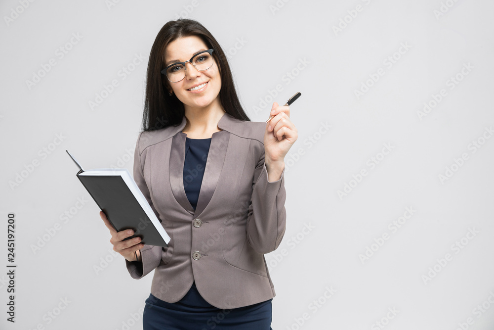 Portrait of a young girl with glasses with a diary in her hands isolated on a light background