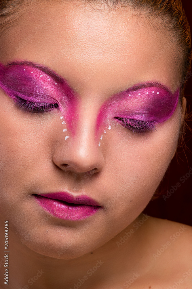 Beautiful young girl portrait, with purple and pink makeup, closeup, eyes closed looking down
