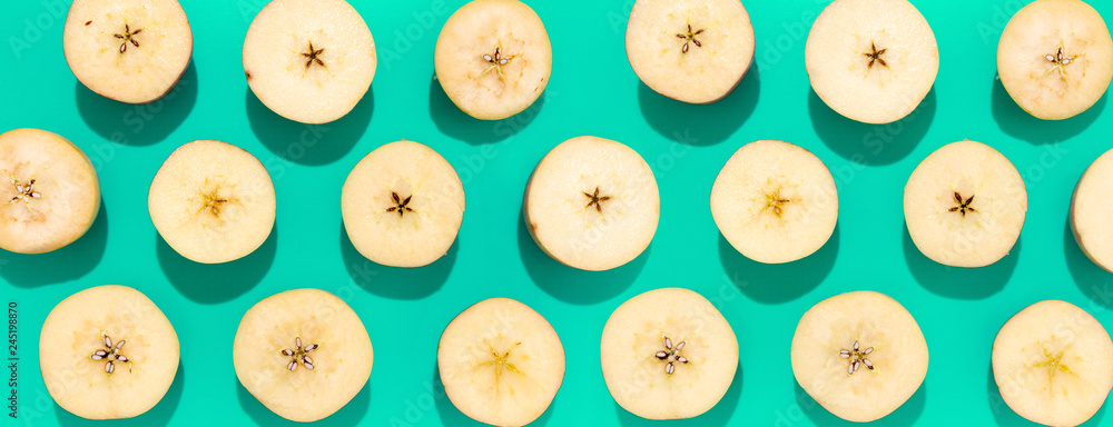 Apples halves in lines with hard shadow on aqua background, flat lay image.