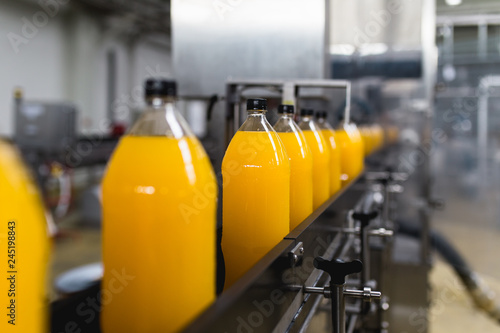 Foto Bottling factory - Orange juice bottling line for processing and bottling juice into bottles