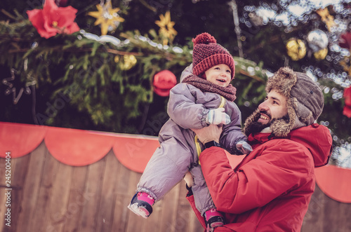 Handsome bearded young dad and his little cute little child daughter are having fun outdoor in winter. Enjoying spending time together. Family concept.