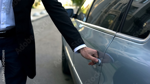 Driver opening car door to young respectable oligarch, professional chauffeur