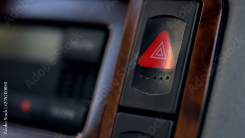 Car hazard warning flasher button on dashboard, emergency situations threat