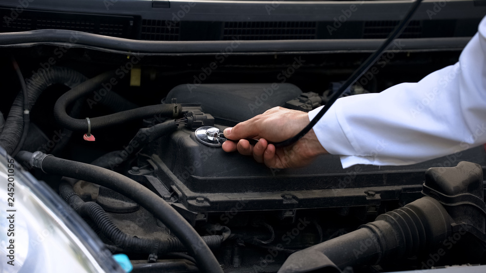 Examination of automobile with stethoscope, concept of qualified car diagnostics Examination of automobile with stethoscope, concept of qualified car diagnostics