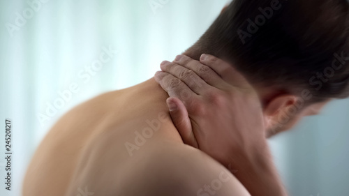 Young man suffering from neck pain, medical and healthcare concept, close up