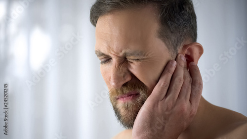 Konstfotografi Man holding his aching ear, suffering from otitis, sudden hearing loss, close up