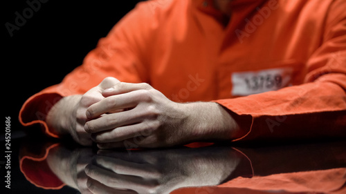 Hand of male prisoner, inmate giving evidence in detention room, cooperation