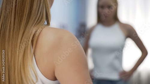Blonde girl standing near mirror at home and posing, personal style, attraction