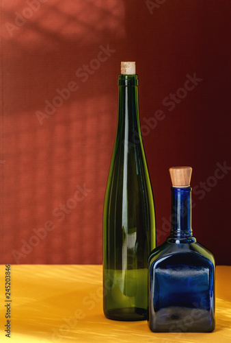 Two colored bottles on a yellow-red textural background. Art still-life in the minimalism and pop-up style collaboration.