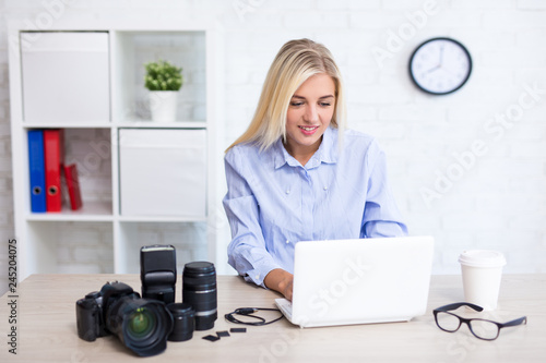 woman photographer sitting with computer and photography equipment in modern office