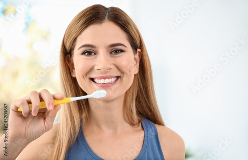 Portrait of woman with toothbrush on blurred background  space for text. Personal hygiene