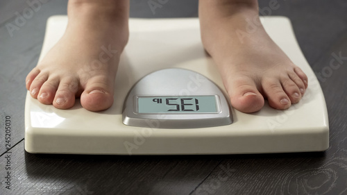 Normal healthy body weight, woman standing on scales to measure dieting results photo