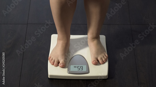 Woman measuring body weight on scales, healthy dieting, balanced nutrition photo