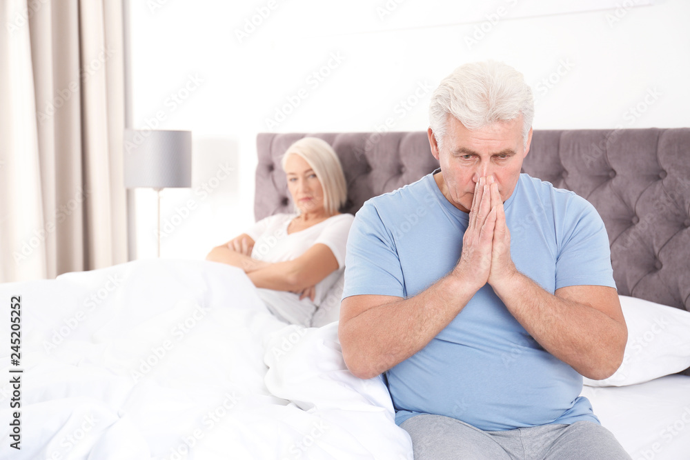 Mature couple with relationship problems ignoring each other in bedroom Mature couple with relationship problems ignoring each other in bedroom
