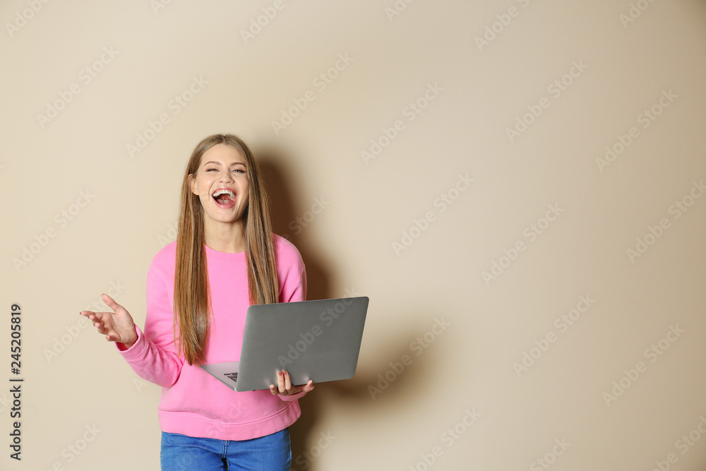 Emotional young woman with laptop celebrating victory on color background. Space for text Emotional young woman with laptop celebrating victory on color background. Space for text