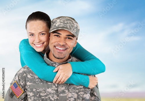 Smiling soldier with his wife standing against background