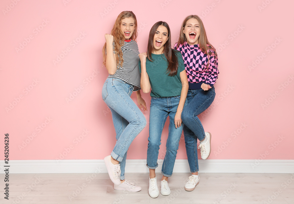 Fototapeta premium Young women celebrating victory near color wall