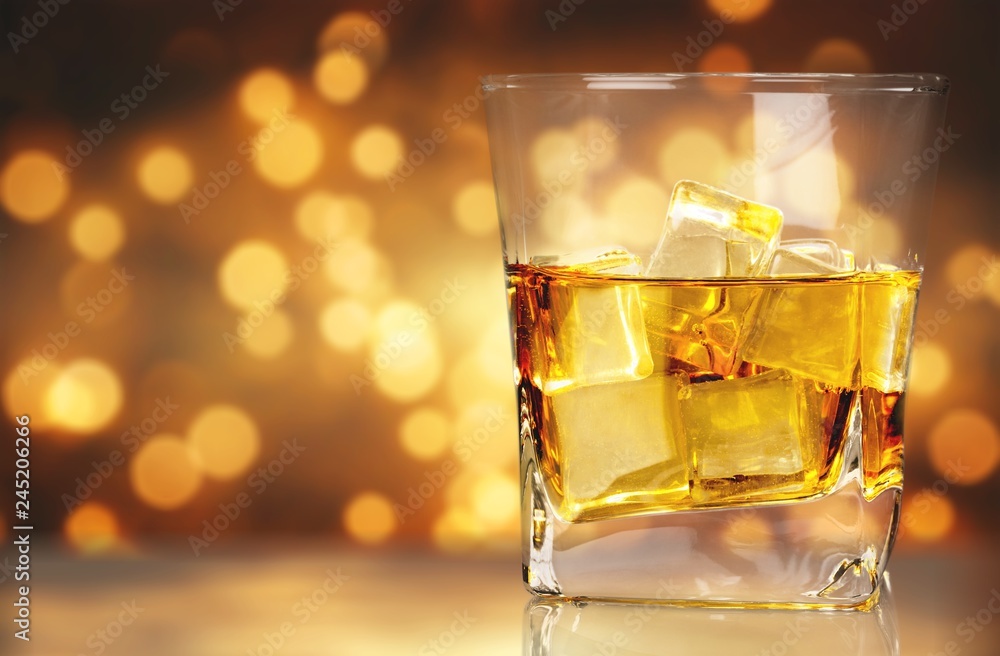 Glass of whiskey and Ice on wooden table on blurred background Glass of whiskey and Ice on wooden table on blurred background