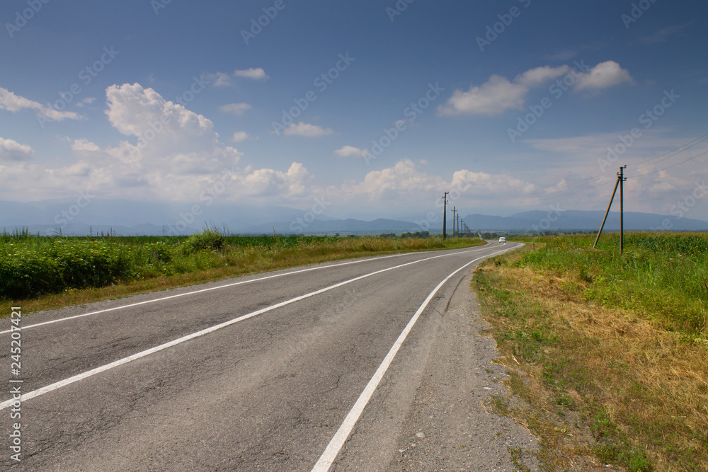Landscape with rocks, sunny sky with clouds and beautiful asphalt road in summer. Highway in mountains.