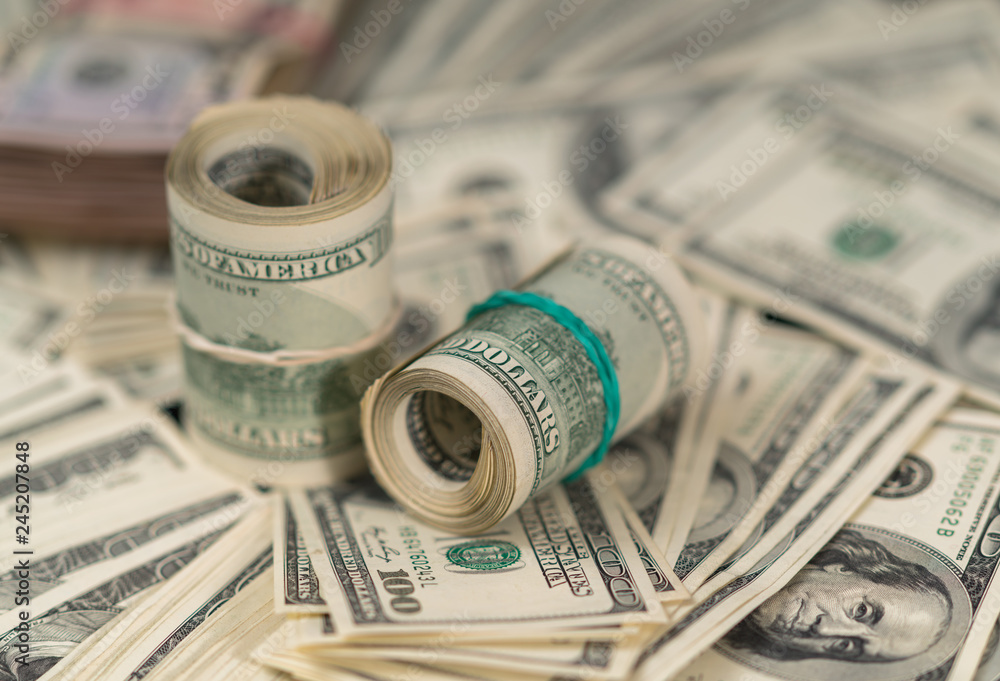 Rolls of 100 dollar bills on piles of money Rolls of 100 dollar bills on piles of money